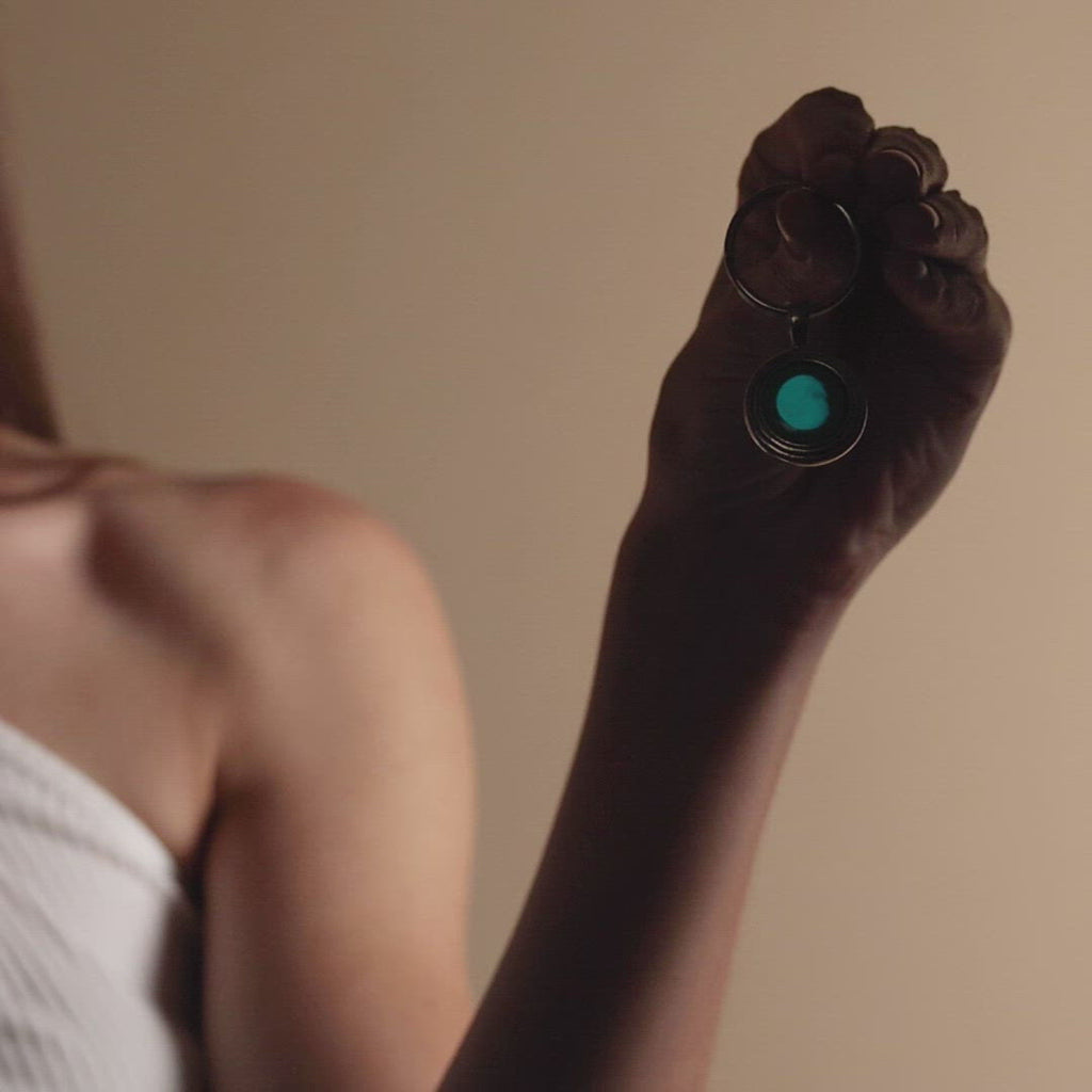 Video of woman holding Regio Keychain in Pewter in the dark, Glow in the dark.