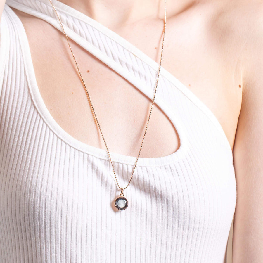 Woman wearing gold plated moon phase pendant necklace with beaded chain